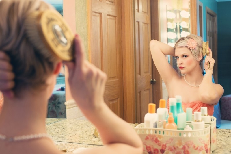 woman-sitting-in-front-of-mirror-and-combing-hair
