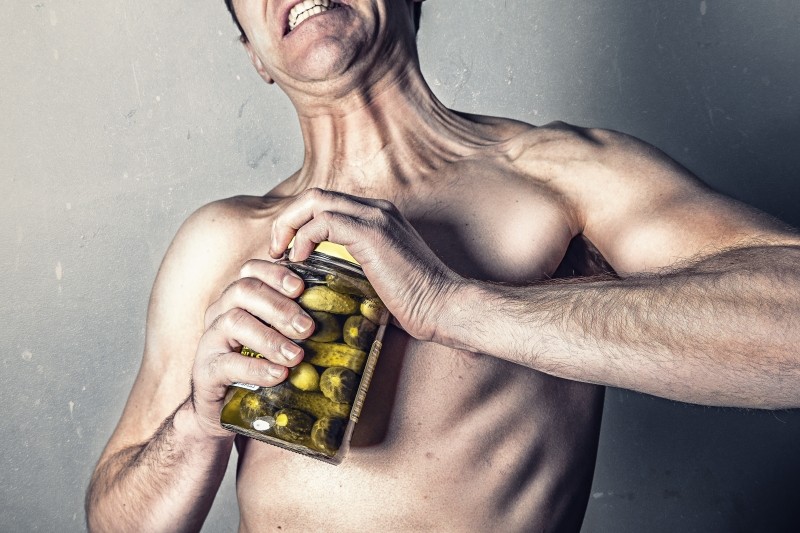 shirtless-man-trying-to-open-jar-with-pickles