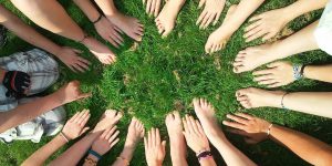 「ラストアイドルとは」という記事中のイメージ画像です。芝生の上に輪を描くように、たくさんの女性が手や足を差し出しています。