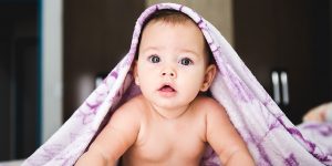 赤ちゃんの寝返りについて書かれた記事のイメージ画像です。うつぶせの赤ちゃんが両手で体を支えてこちらを見ています。